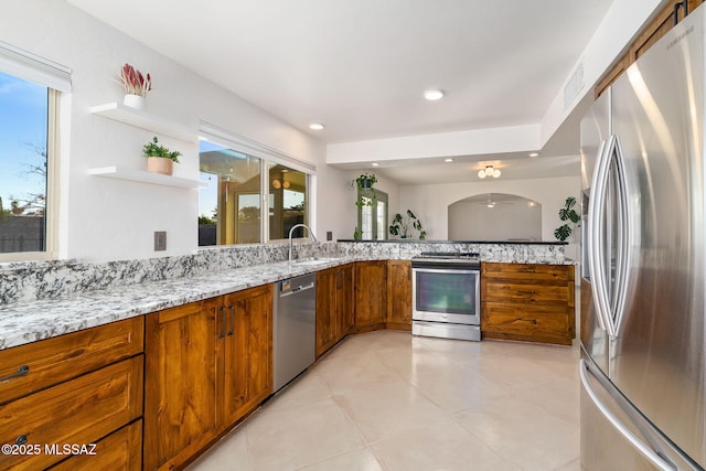 kitchen with sink, light tile patterned floors, light stone countertops, and appliances with stainless steel finishes