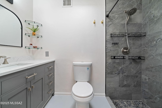 bathroom with vanity, toilet, and tiled shower