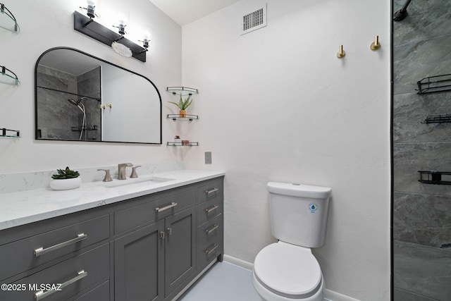 bathroom with tiled shower, vanity, and toilet