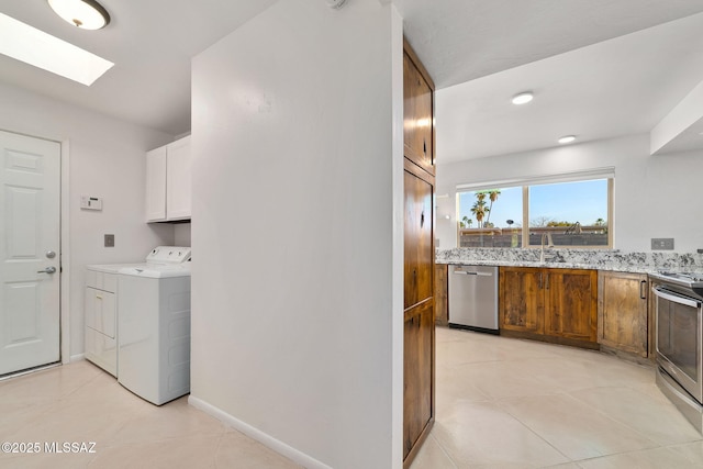 laundry area featuring a skylight, separate washer and dryer, sink, and light tile patterned floors