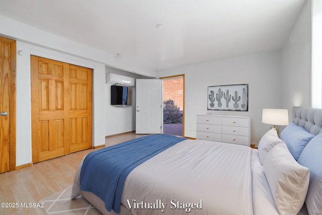 bedroom featuring a wall mounted AC and light hardwood / wood-style flooring