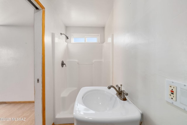 bathroom featuring hardwood / wood-style flooring, a shower, and sink