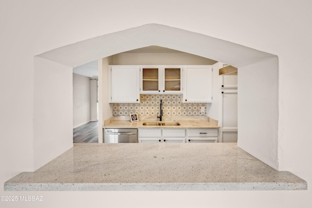 kitchen featuring dishwasher, sink, white cabinets, decorative backsplash, and light stone counters