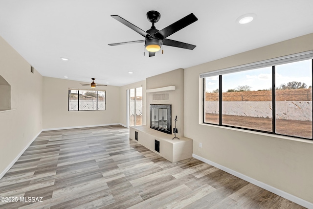 unfurnished living room featuring ceiling fan, a healthy amount of sunlight, and light hardwood / wood-style flooring