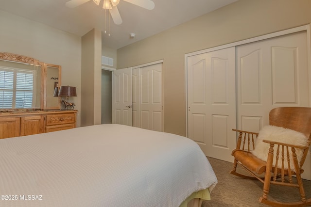 carpeted bedroom with two closets and ceiling fan