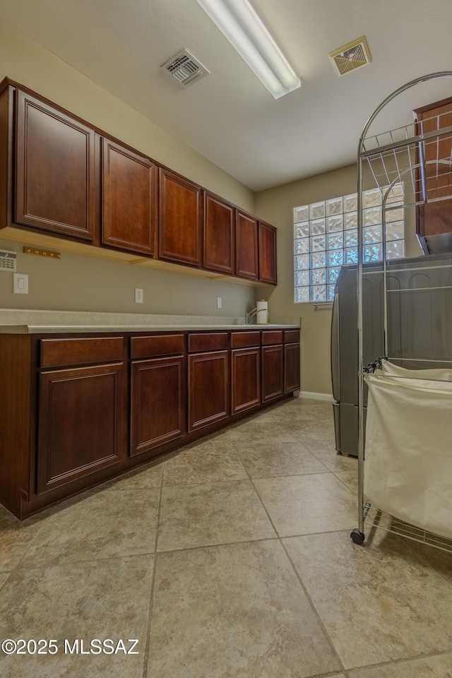 laundry room with cabinets, washer / dryer, and light tile patterned floors