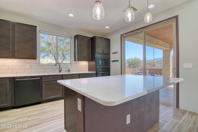 kitchen featuring pendant lighting, tasteful backsplash, sink, a center island, and black appliances