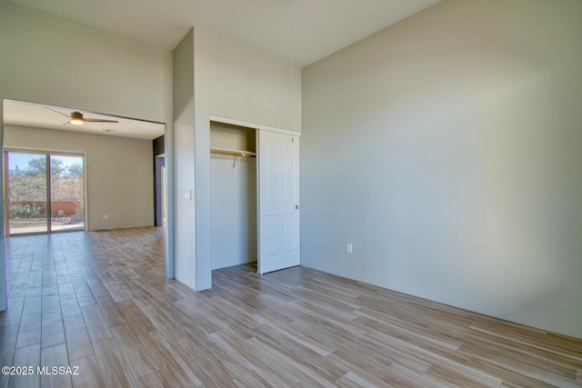 unfurnished bedroom featuring a towering ceiling, access to outside, light hardwood / wood-style floors, and a closet