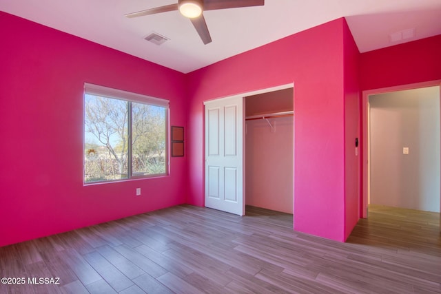 unfurnished bedroom featuring hardwood / wood-style floors, ceiling fan, and a closet