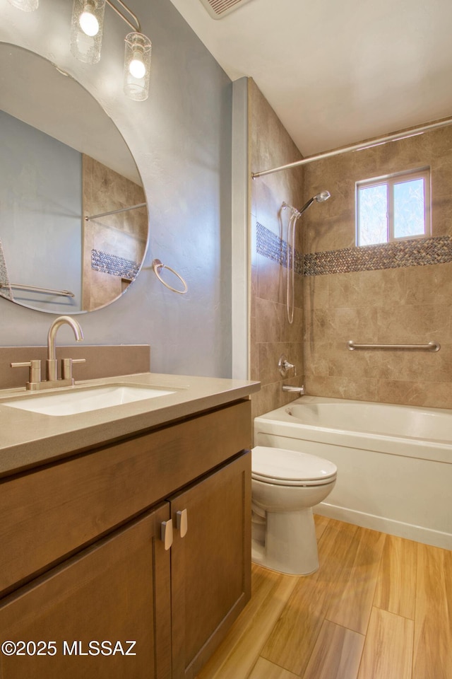 full bathroom with vanity, tiled shower / bath combo, toilet, and hardwood / wood-style flooring