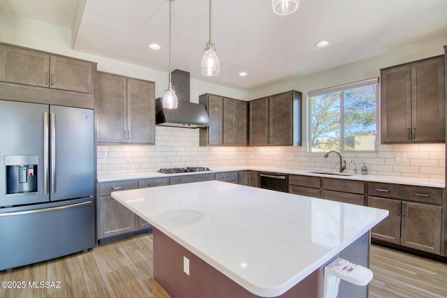 kitchen featuring a kitchen island, sink, decorative backsplash, stainless steel appliances, and wall chimney range hood