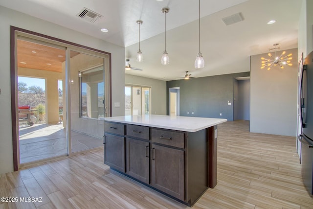 kitchen with light wood-type flooring, decorative light fixtures, dark brown cabinets, and a kitchen island