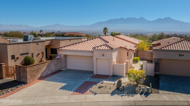 view of front facade with a garage, concrete driveway, a tiled roof, a mountain view, and stucco siding