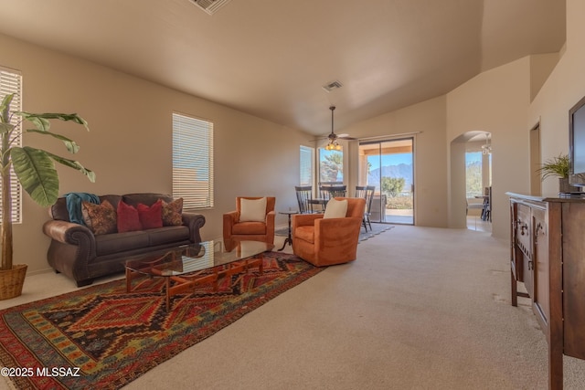 living room with visible vents, arched walkways, a ceiling fan, light colored carpet, and high vaulted ceiling