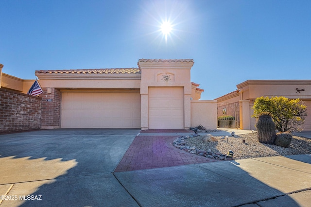 mediterranean / spanish-style house featuring a garage, fence, a tile roof, concrete driveway, and stucco siding