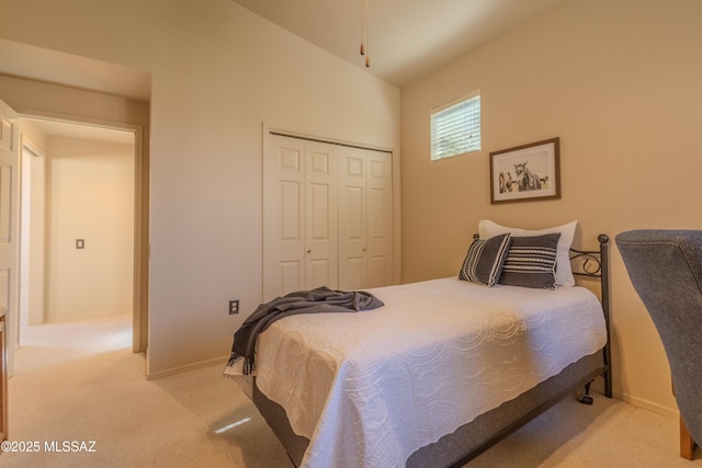 bedroom with vaulted ceiling, a closet, baseboards, and light colored carpet