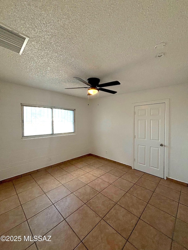 spare room featuring tile patterned flooring, visible vents, ceiling fan, and a textured ceiling