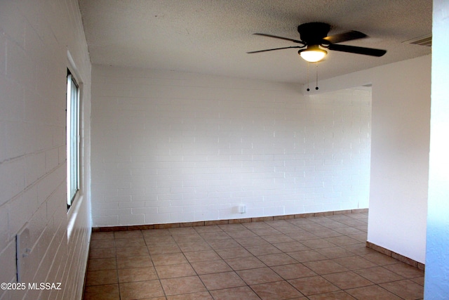 empty room featuring a textured ceiling, light tile patterned floors, visible vents, and a ceiling fan