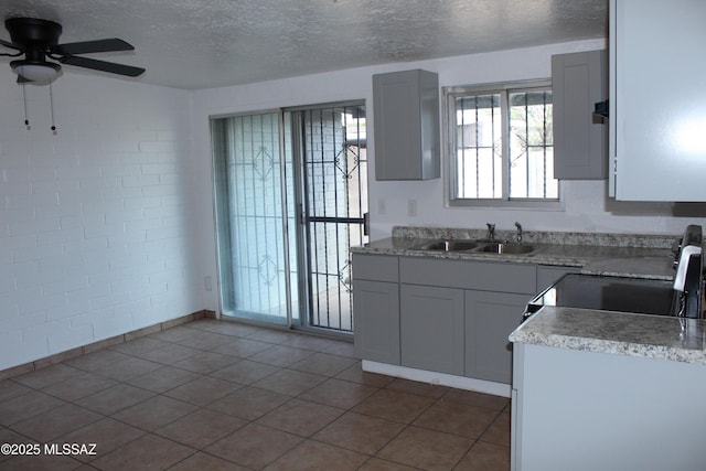 kitchen with a textured ceiling, light countertops, a sink, and range