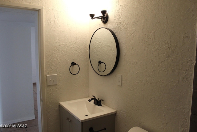 bathroom featuring a textured wall and vanity