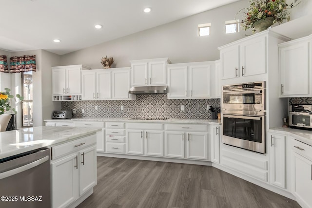 kitchen featuring white cabinetry, light stone counters, light hardwood / wood-style flooring, stainless steel appliances, and backsplash