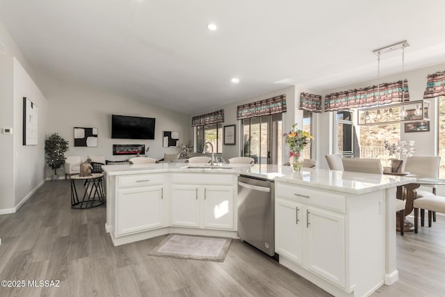 kitchen featuring vaulted ceiling, dishwasher, an island with sink, white cabinets, and light wood-type flooring