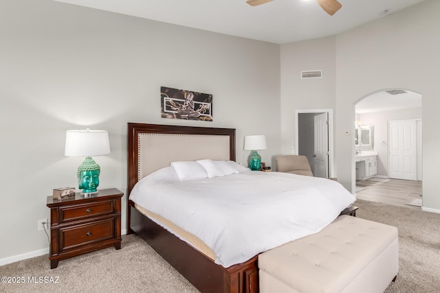 bedroom featuring connected bathroom, light carpet, and ceiling fan