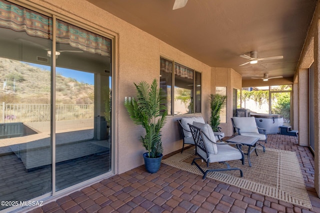 view of patio featuring a hot tub, a mountain view, and ceiling fan