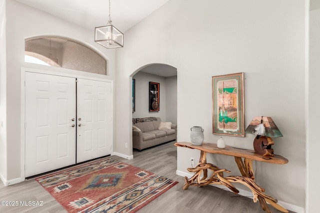 foyer entrance featuring high vaulted ceiling, light hardwood / wood-style floors, and a chandelier