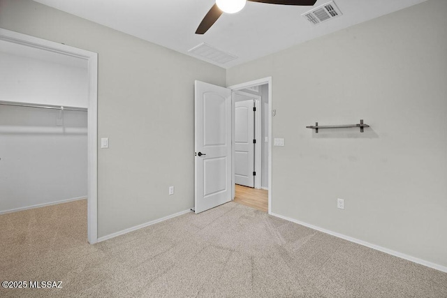 unfurnished bedroom featuring ceiling fan, light colored carpet, a closet, and a walk in closet