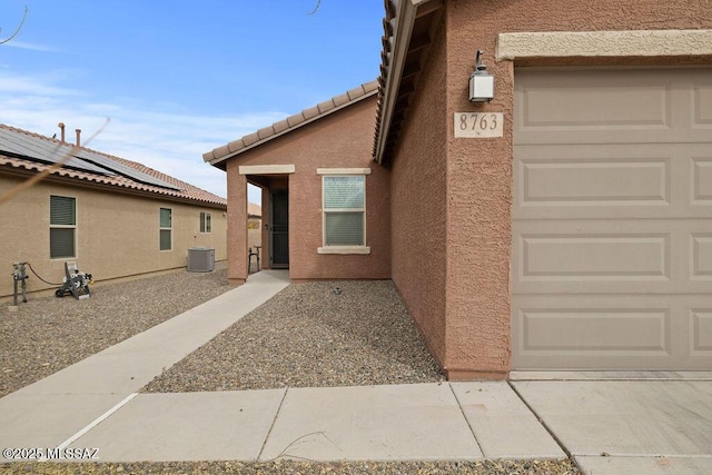 view of exterior entry featuring a garage and central AC