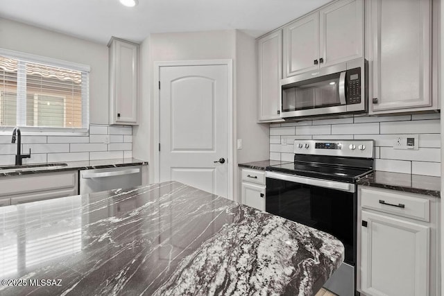 kitchen with dark stone countertops, sink, backsplash, and appliances with stainless steel finishes