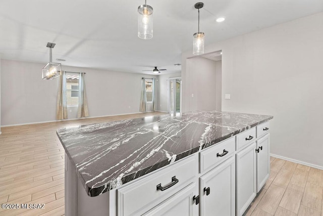 kitchen featuring white cabinetry, dark stone countertops, a center island, and pendant lighting