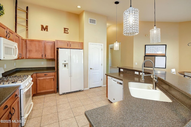 kitchen featuring sink, decorative light fixtures, light tile patterned floors, white appliances, and a high ceiling