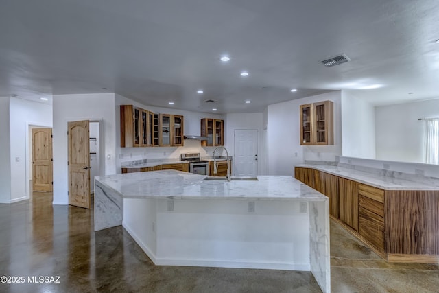 kitchen featuring a large island, sink, stainless steel range with electric stovetop, concrete floors, and wall chimney exhaust hood