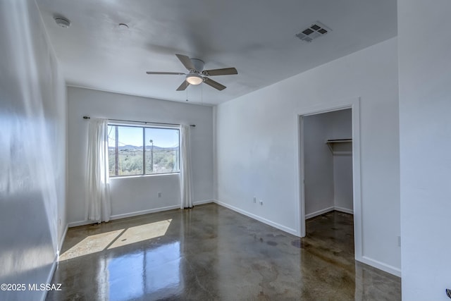 unfurnished bedroom featuring ceiling fan, a walk in closet, and a closet