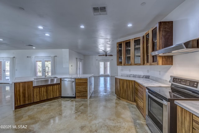 kitchen featuring french doors, sink, appliances with stainless steel finishes, kitchen peninsula, and wall chimney range hood