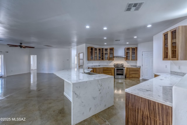 kitchen featuring sink, stainless steel electric range, light stone countertops, an island with sink, and kitchen peninsula