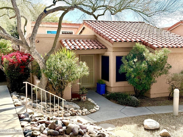 exterior space with a tile roof and stucco siding