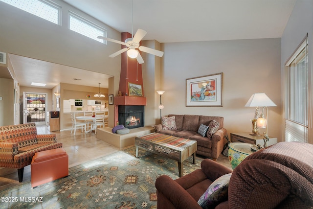 living area featuring light tile patterned floors, a high ceiling, a fireplace, visible vents, and a ceiling fan