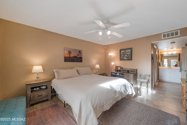 bedroom with tile patterned flooring, visible vents, ceiling fan, and connected bathroom