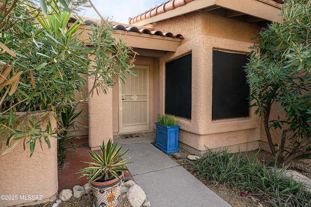 doorway to property featuring a tiled roof and stucco siding