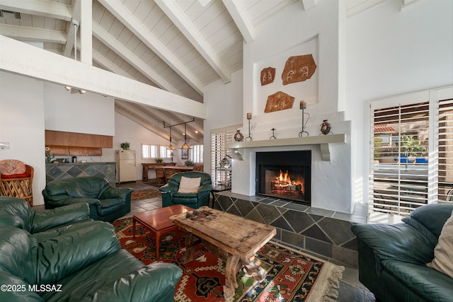 living area with high vaulted ceiling, wood ceiling, a warm lit fireplace, and beamed ceiling