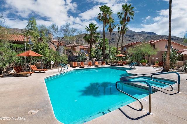 community pool featuring a patio area, fence, and a mountain view