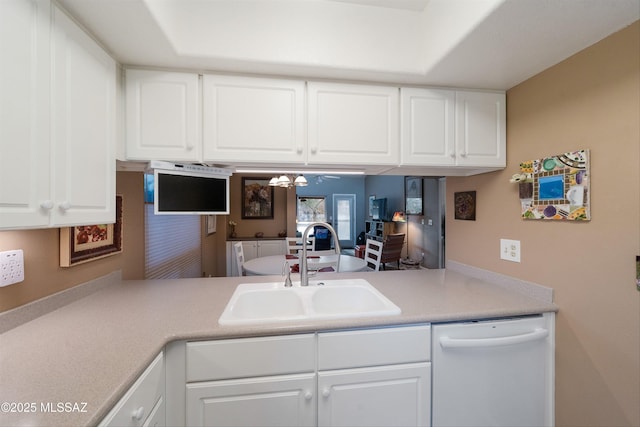 kitchen with white dishwasher, white cabinets, a sink, and light countertops