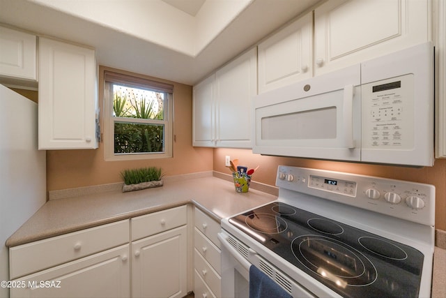 kitchen featuring white appliances, white cabinetry, and light countertops