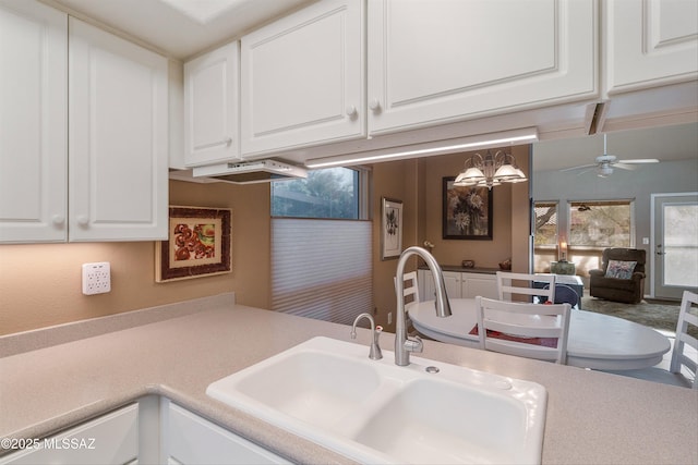 kitchen with light countertops, a sink, and white cabinetry