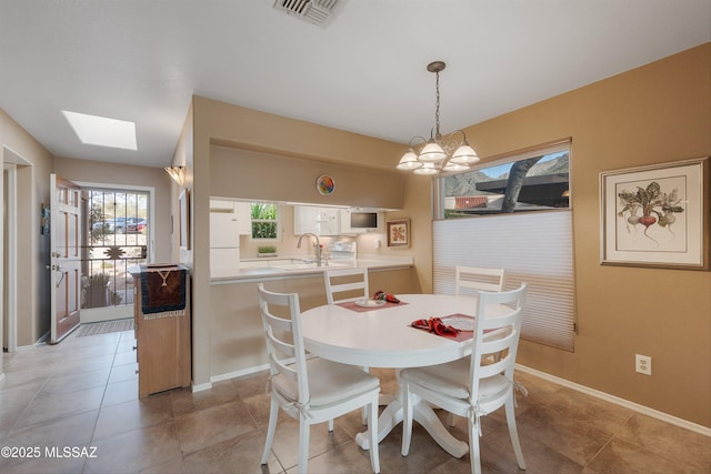 dining area with a skylight, baseboards, visible vents, a chandelier, and light tile patterned flooring