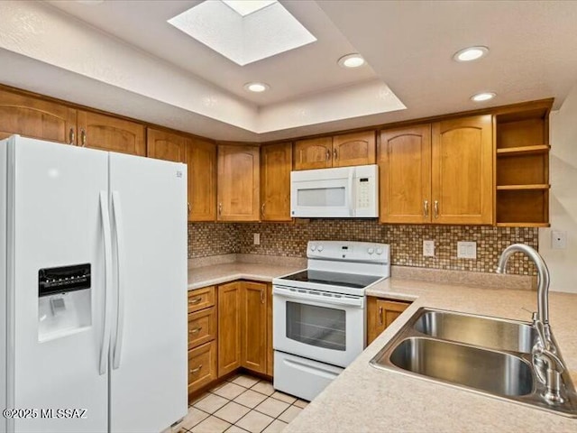 kitchen with tasteful backsplash, sink, white appliances, and a tray ceiling