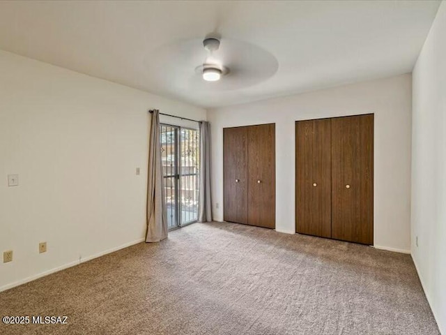 unfurnished bedroom with multiple closets, access to outside, light colored carpet, and ceiling fan